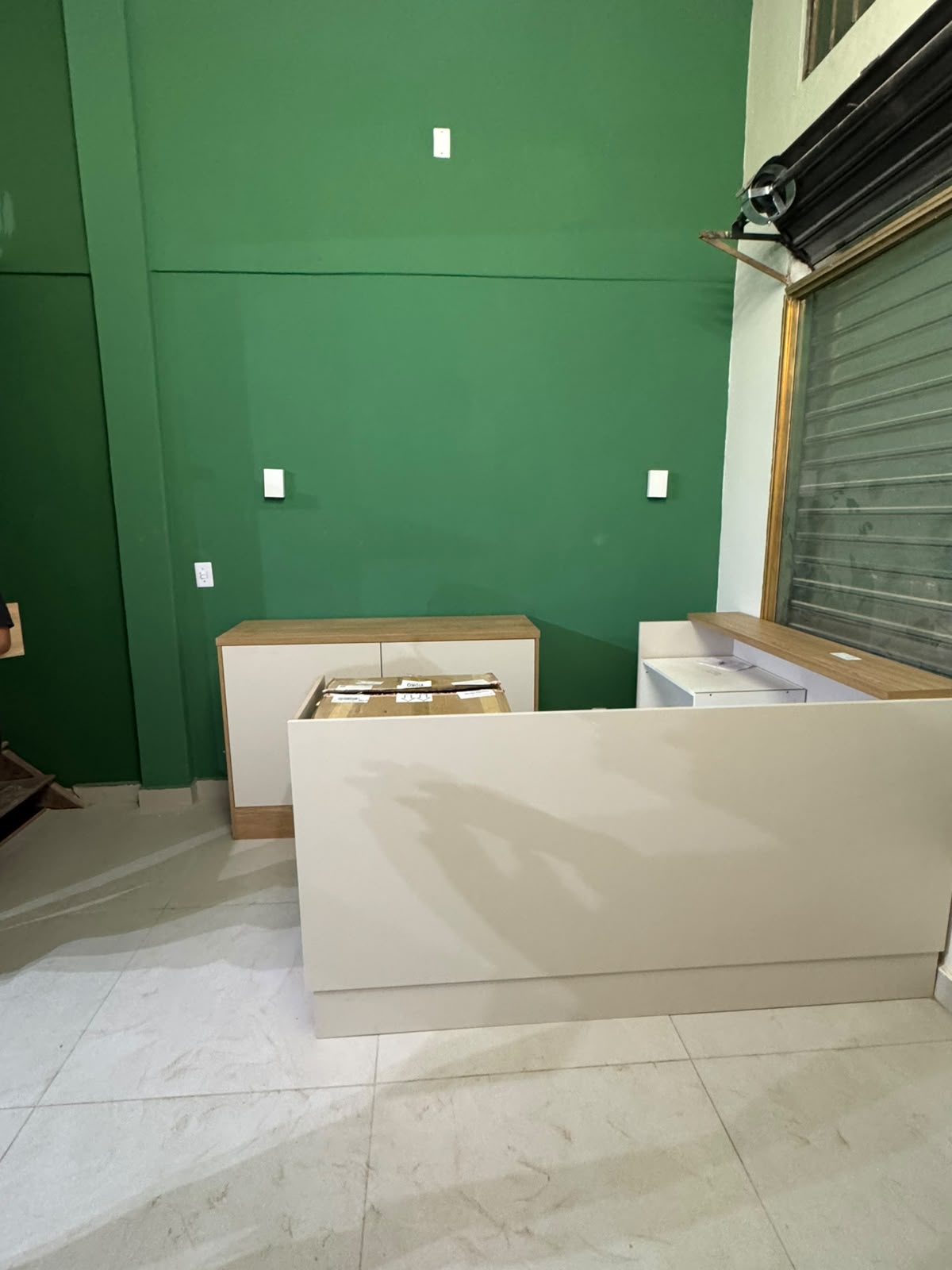 Recepção finalizada com parede verde e porta de aço aberta