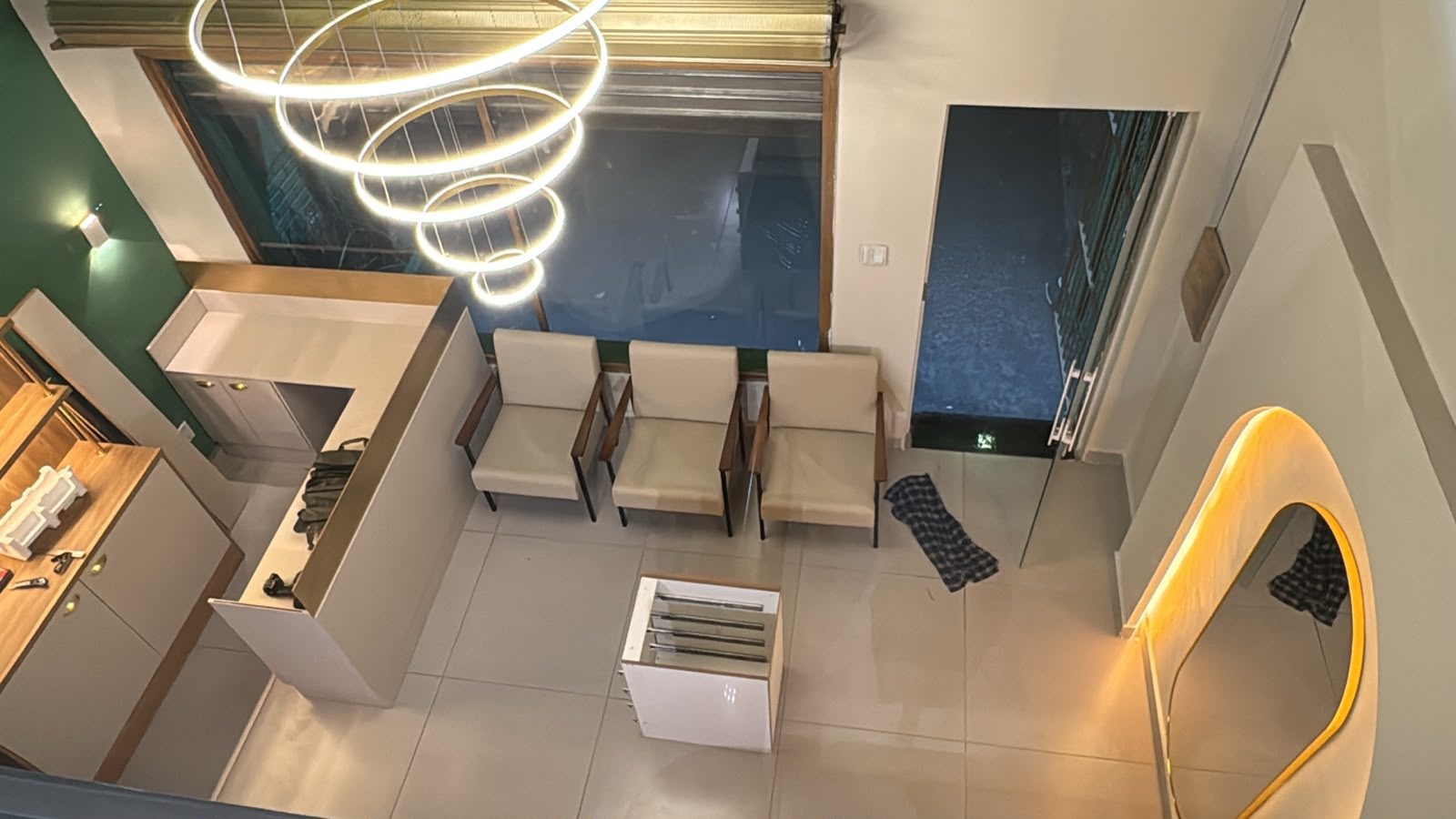 Vista aérea da recepção finalizada, com lustre de aros aceso e poltronas no lugar