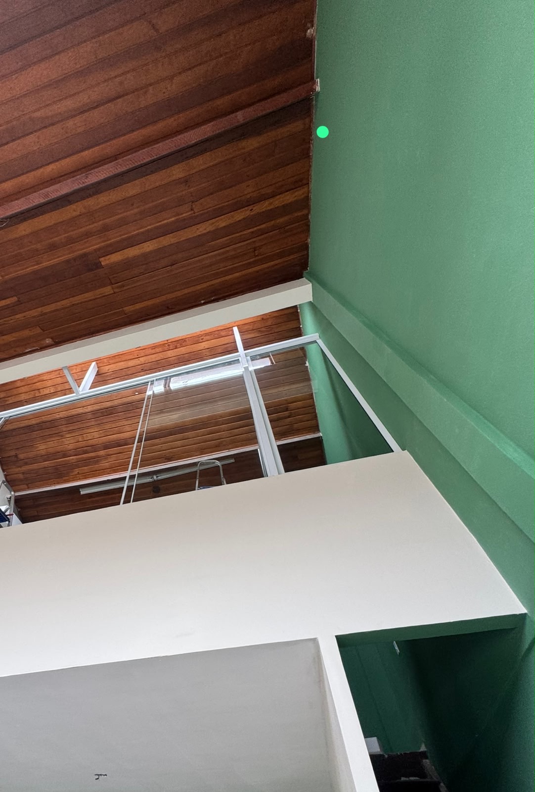 Mezanino VIP visto de cima — vidro, verde e forro de madeira