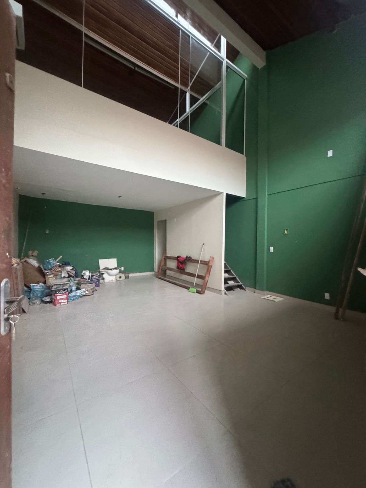 Vista geral do salão — piso assentado, mezanino e guarda-corpo de vidro instalados