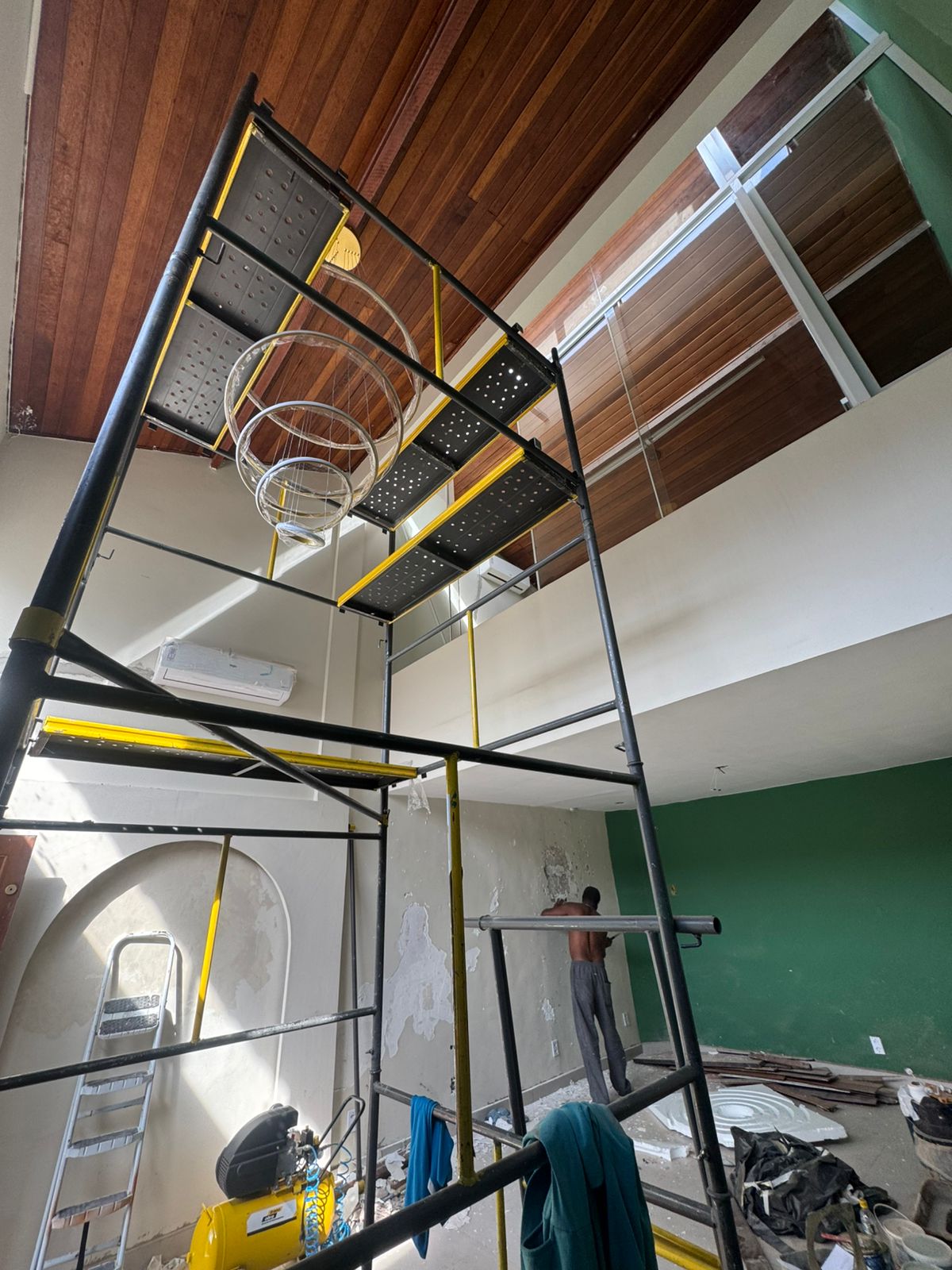 Visão geral da obra — andaime montado, nicho arqueado e parede verde em acabamento