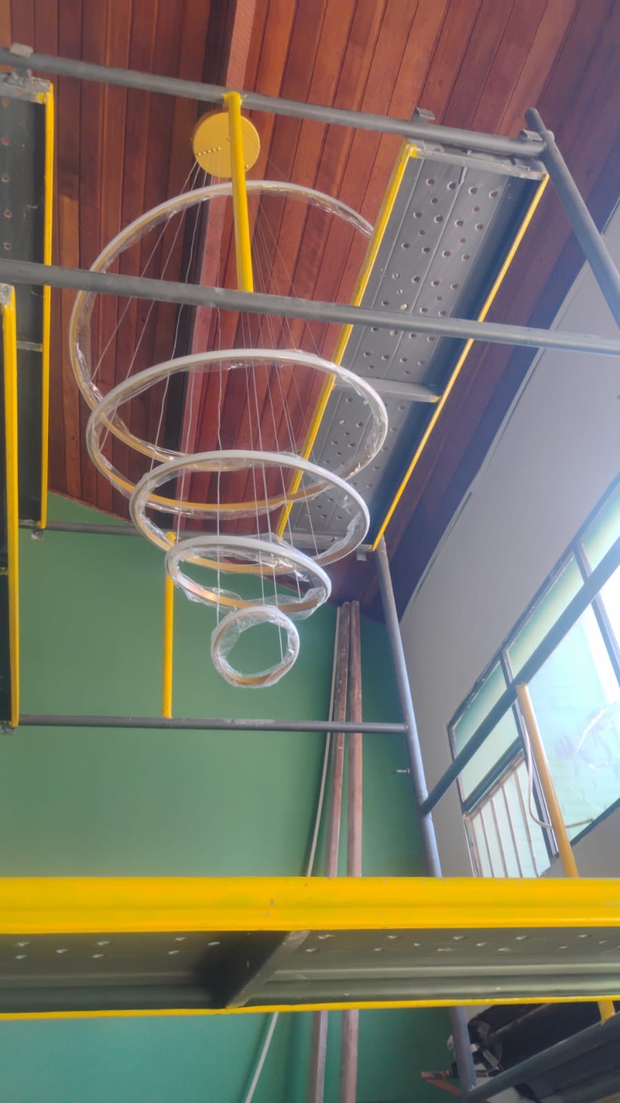 Lustre de aros suspensos sendo instalado no forro de madeira do pé-direito duplo
