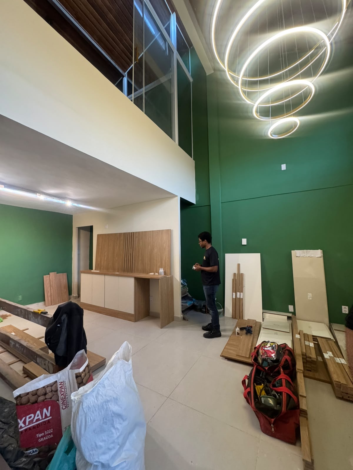 Visão geral do térreo com lustre de aros aceso e balcão de recepção sendo posicionado