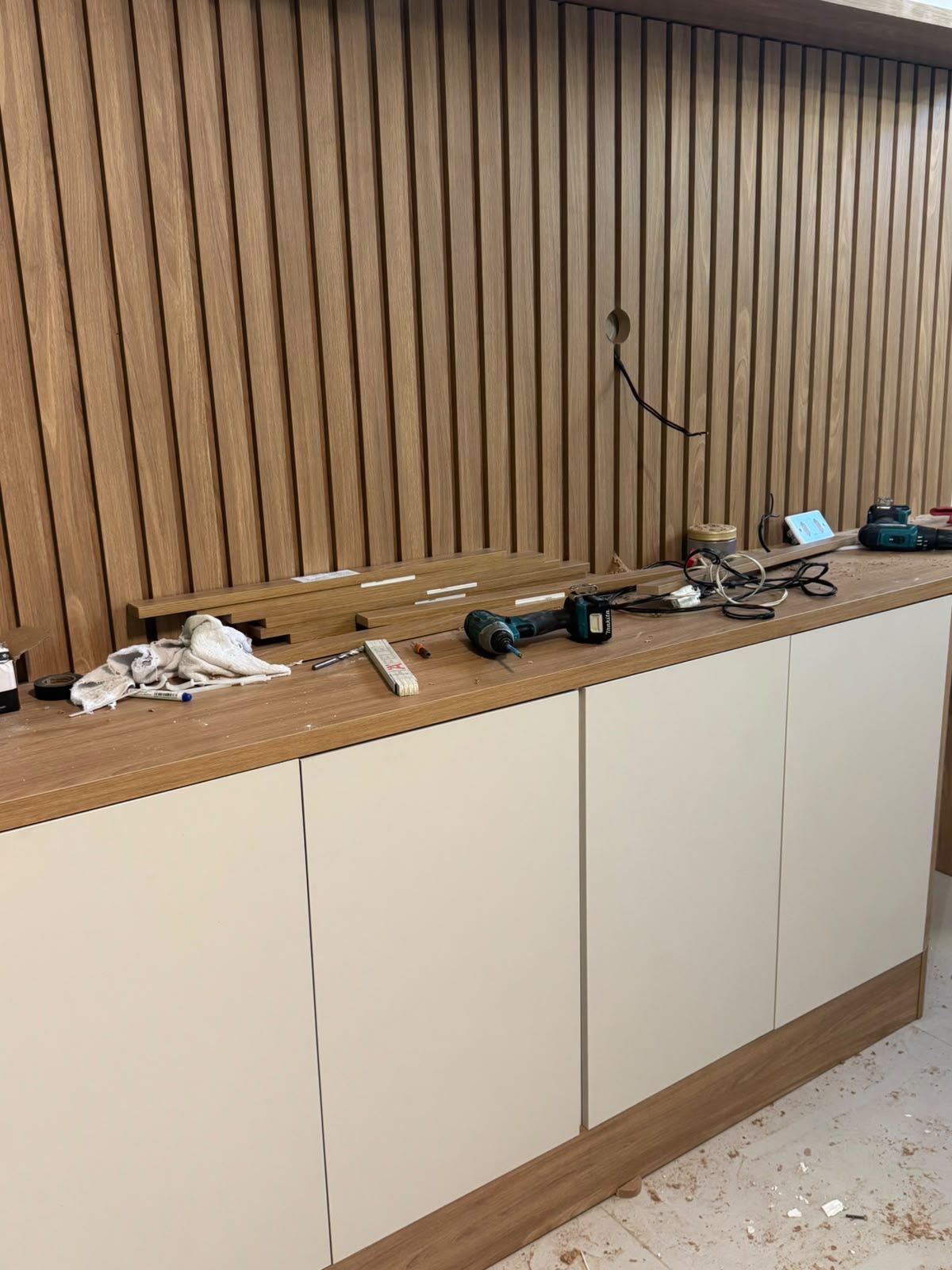 Detalhe do painel ripado em madeira e balcão da recepção em instalação