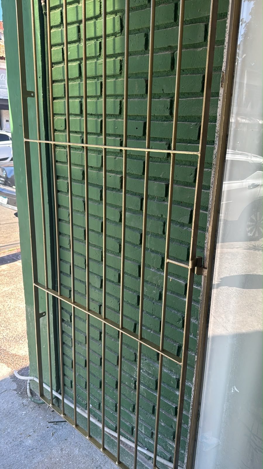 Detalhe da grade dourada na fachada sobre tijolo verde pintado